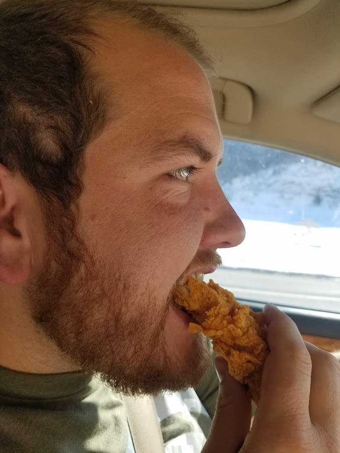 A person take a bite out of a chicken strip.