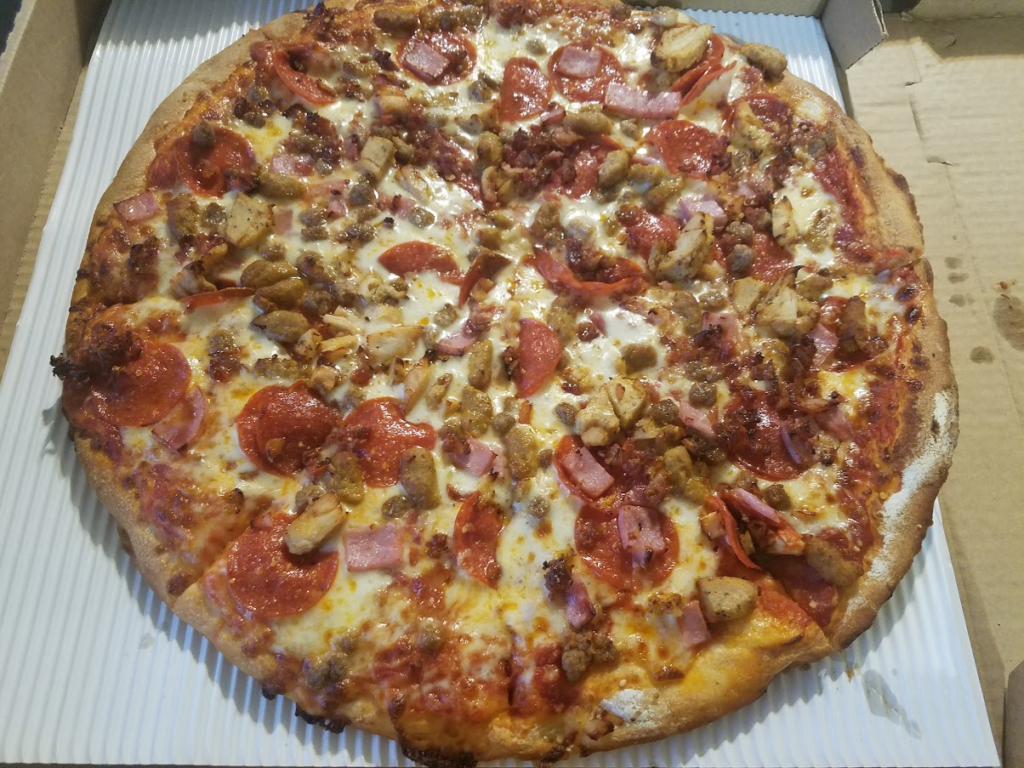 The carnivore pizza, with sausage, pepperoni, ham, chicken, ground Beef, bacon, parmesan, cheese, and marinara sauce. at Ogden Pizzeria  