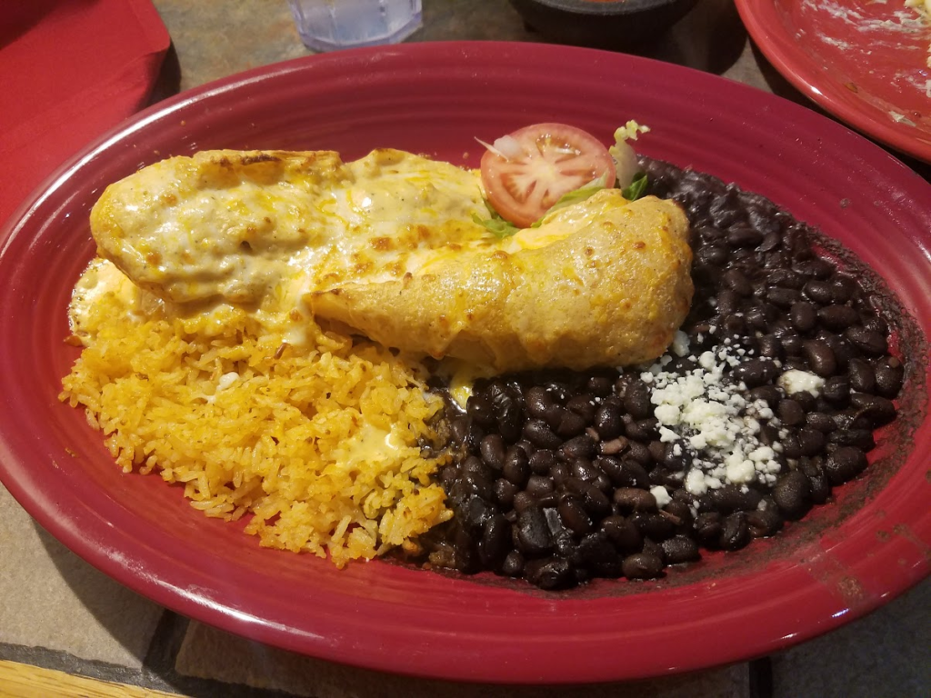 A platter with black beans, chimichangas, and rice.