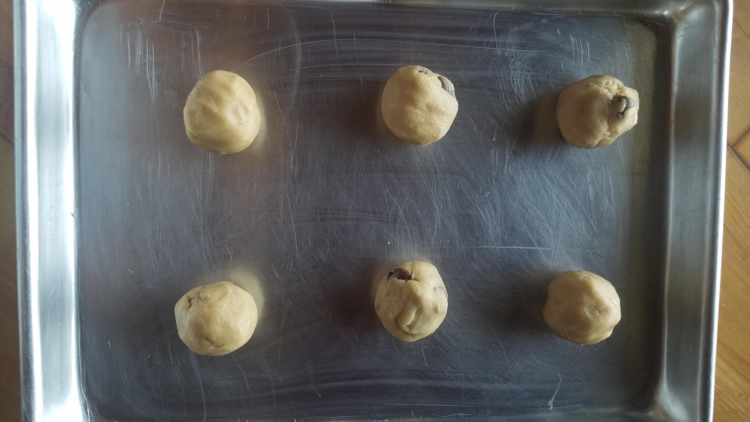 six cookie dough balls on a cookie sheet