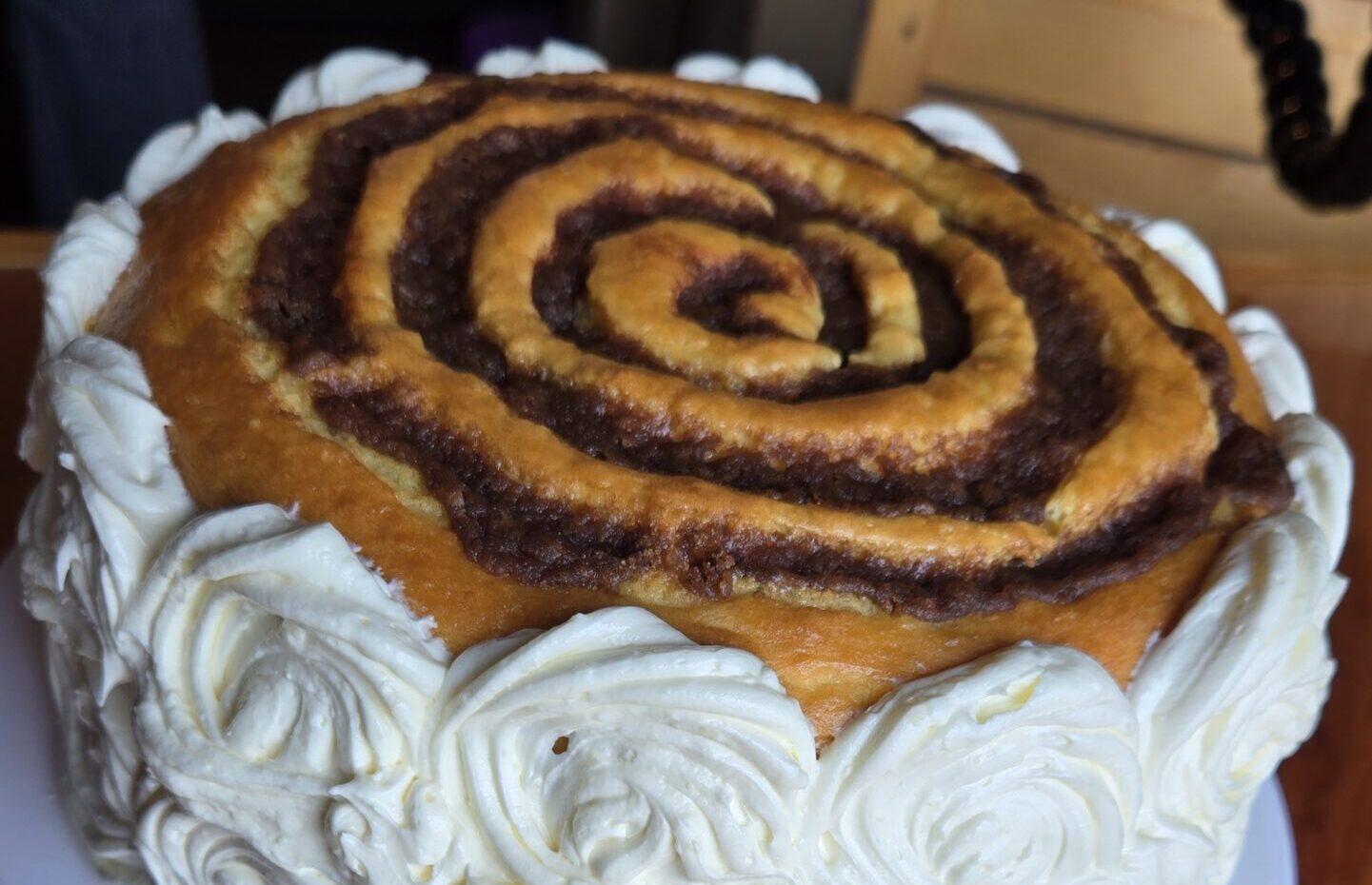 Cinnamon Roll Cake with rosette cream cheese frosting on the outside.